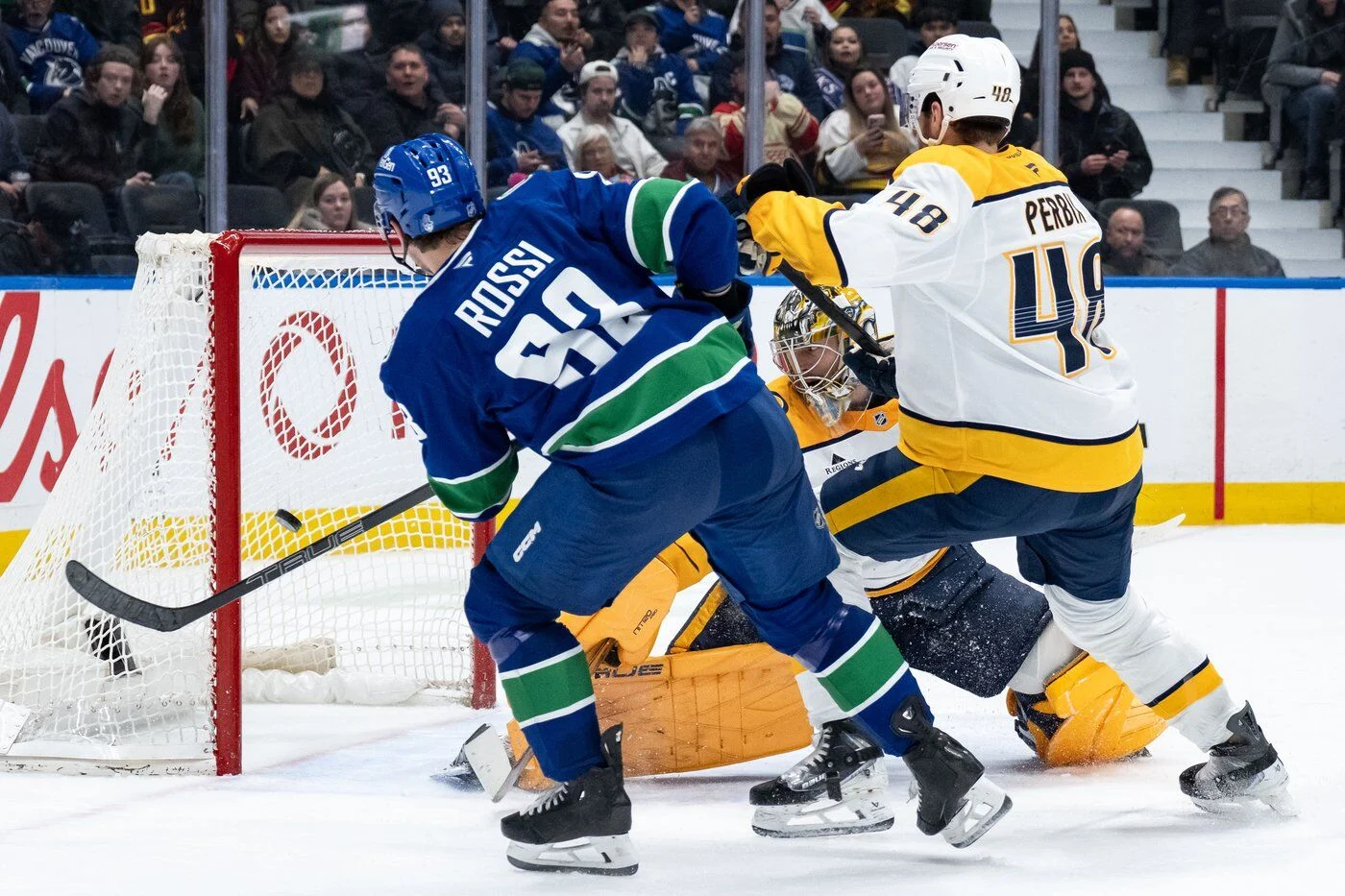 Vancouver Canucks' Marco Rossi (93) scores on Nashville Predators goaltender Juuse Saros (74) as Nick Perbix (48)
